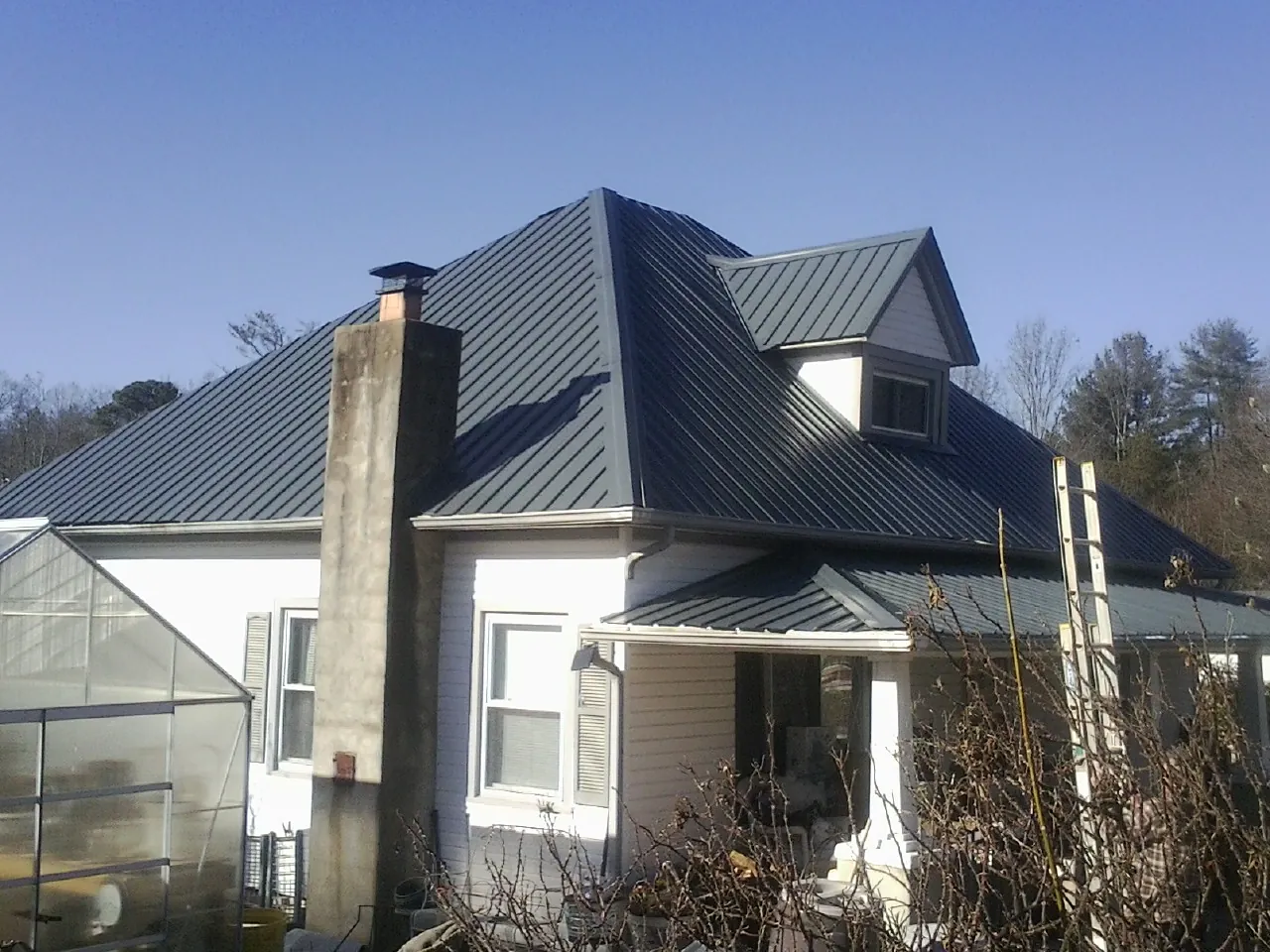 Dark blue standing seam metal roof on a white farmhouse with dormer — Slate & Tile Roof Repair by Roofing Brothers in Colrain