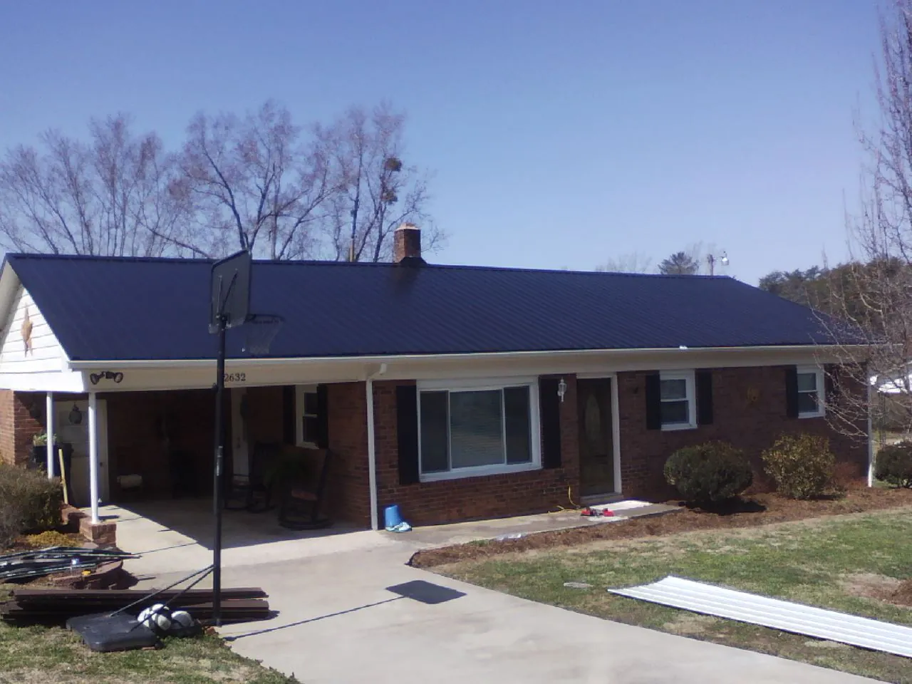 Finished dark blue metal roof on a brick ranch with a carport in Colrain