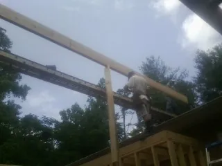 Carpenter setting a ridge beam over a new addition frame — Ice Dam Removal by Roofing Brothers in Colrain