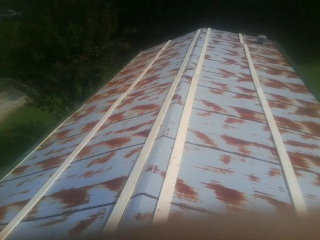 Rusted metal roof panels with new wood purlins before replacement — Storm Damage Roof Repair in Colrain by Roofing Brothers