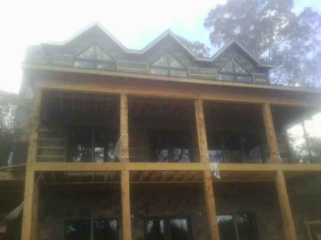 Dormers and porch framing on a large log home under construction — Roof Coating work by our crew in Colrain