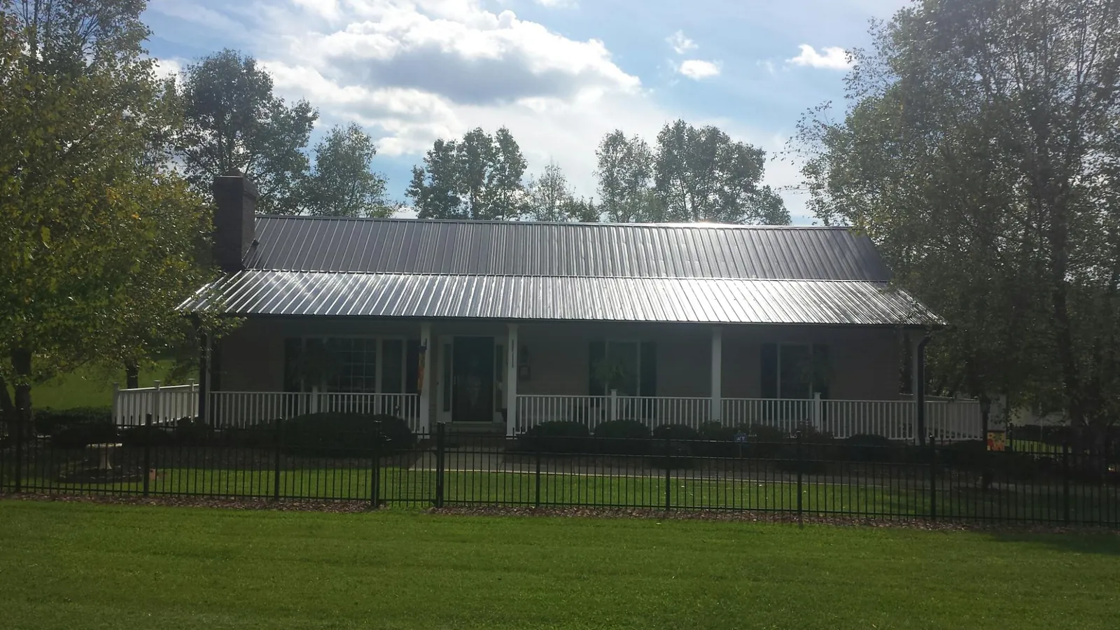 Gray metal roof on a brick ranch with a full width front porch — Gutter Guard Installation work by our crew in Colrain