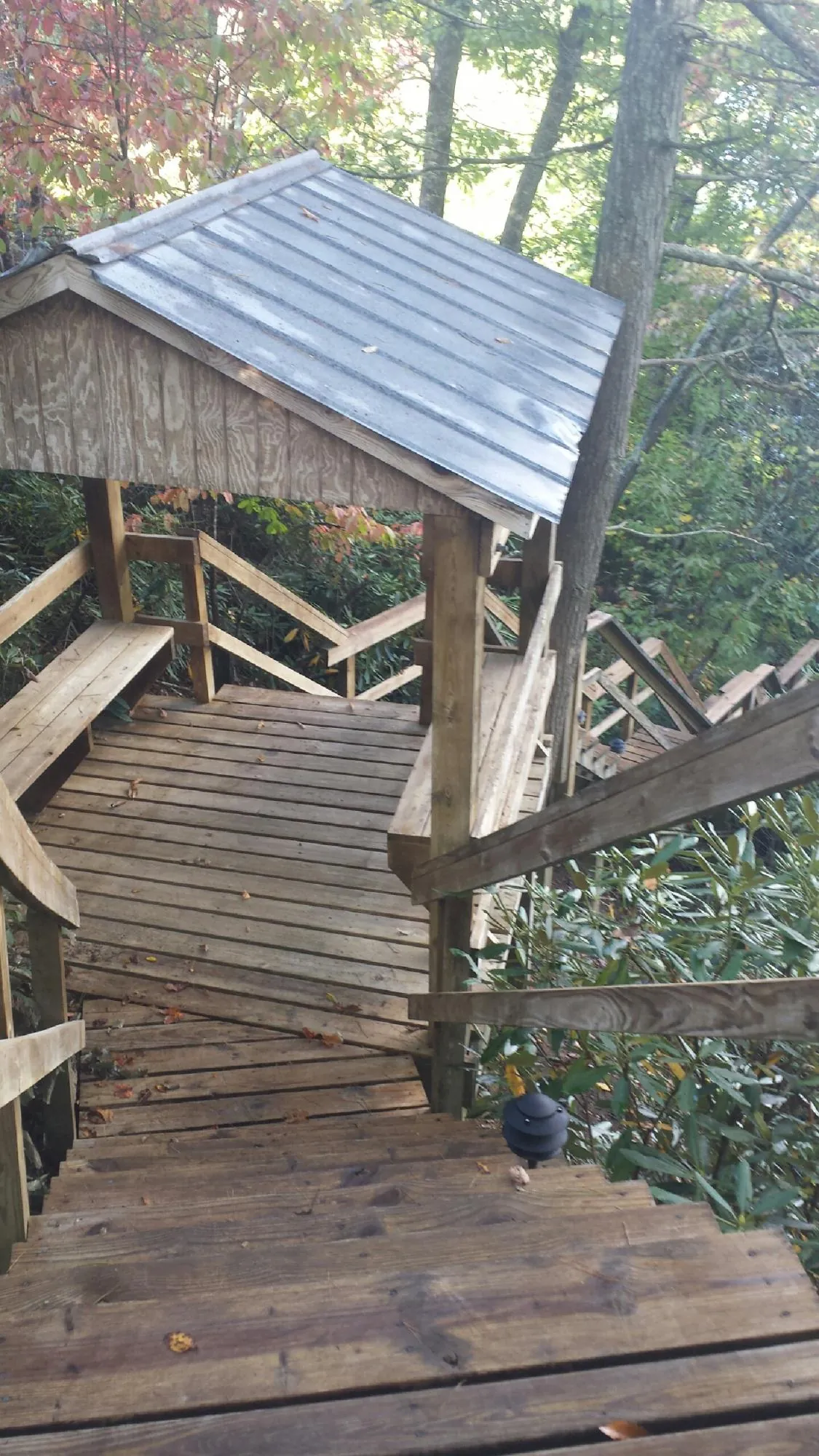 Metal roofed shelter over wooden steps on a wooded walkway — Skylight Repair & Installation work by our crew in Colrain